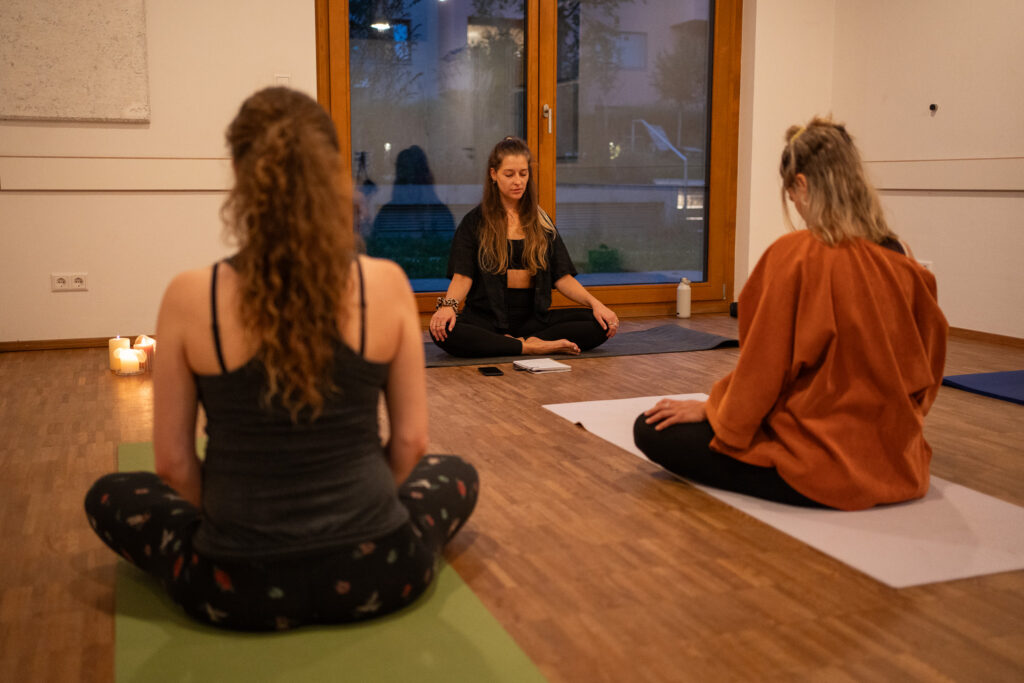 Frauen beim Meditieren im Yoga-Studio, entspannte Abendstimmung, Yoga-Fotoshooting