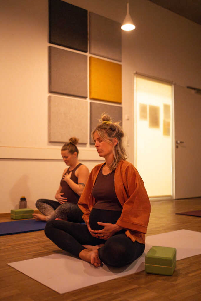 Meditation im Yoga-Studio: Frau sitzt im Schneidersitz auf der Matte, Yoga Fotosession