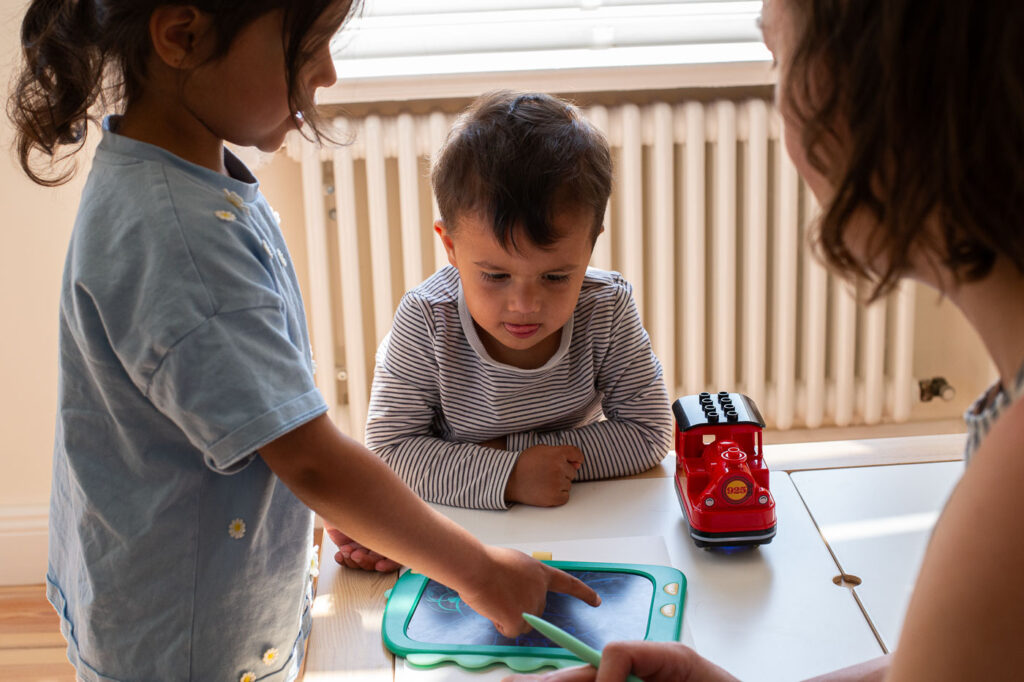 Geschwister spielen gemeinsam am Tisch bei natürlichem Tageslicht, Fotografin Esslingen Stuttgart