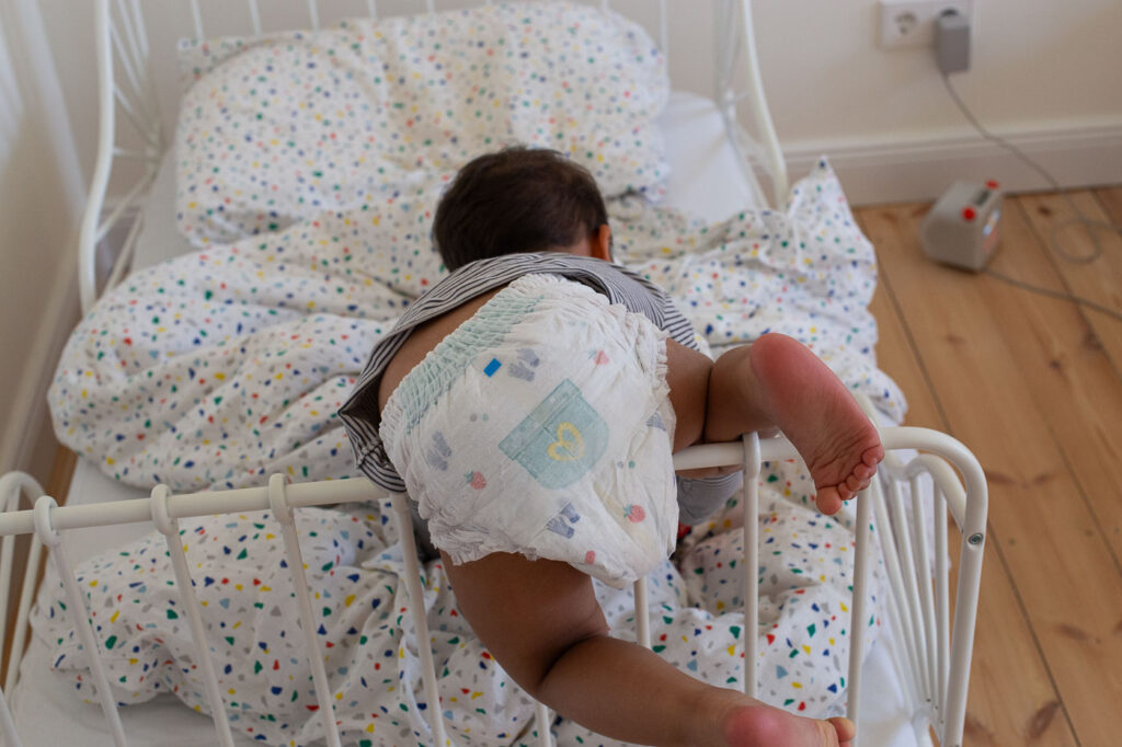 Kleinkind klettert im Bett, Familienreportage Esslingen