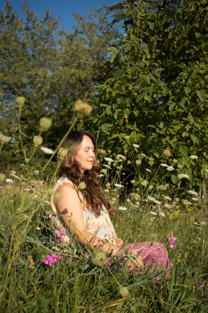 Romantisches Schwangerschaftsfoto: Frau sitzt im Blumenfeld