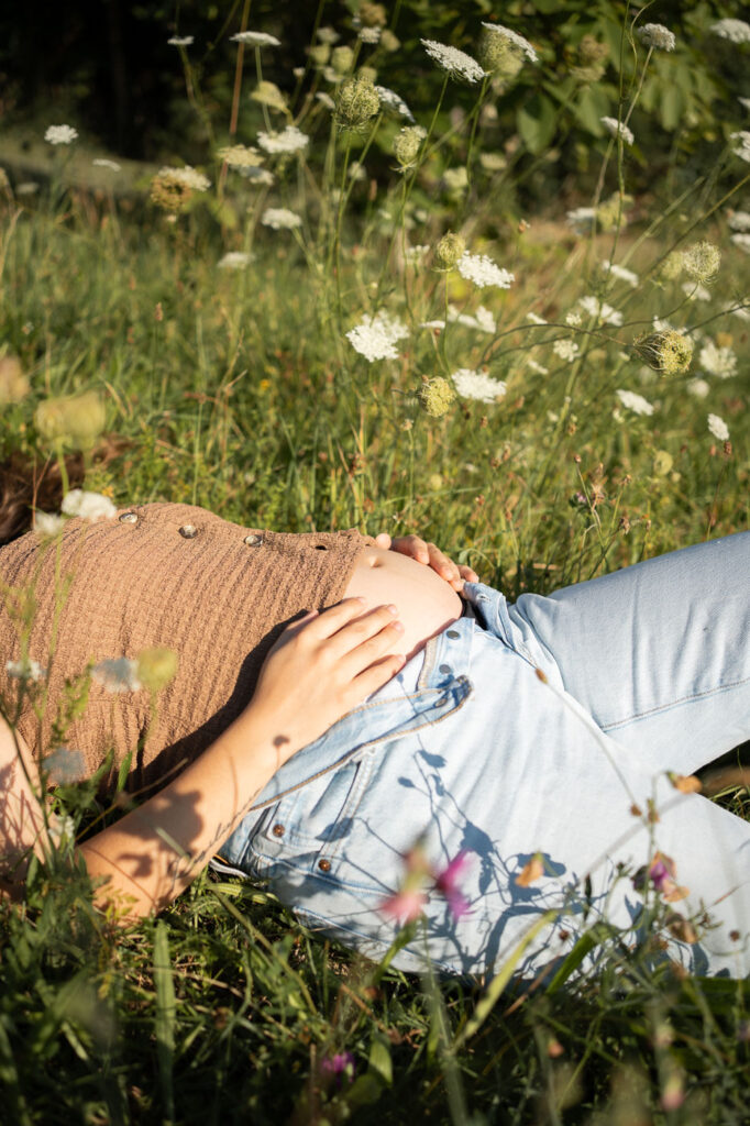 Entspanntes Schwangerschafts-Shooting: Frau liegt mit Babybauch im Gras