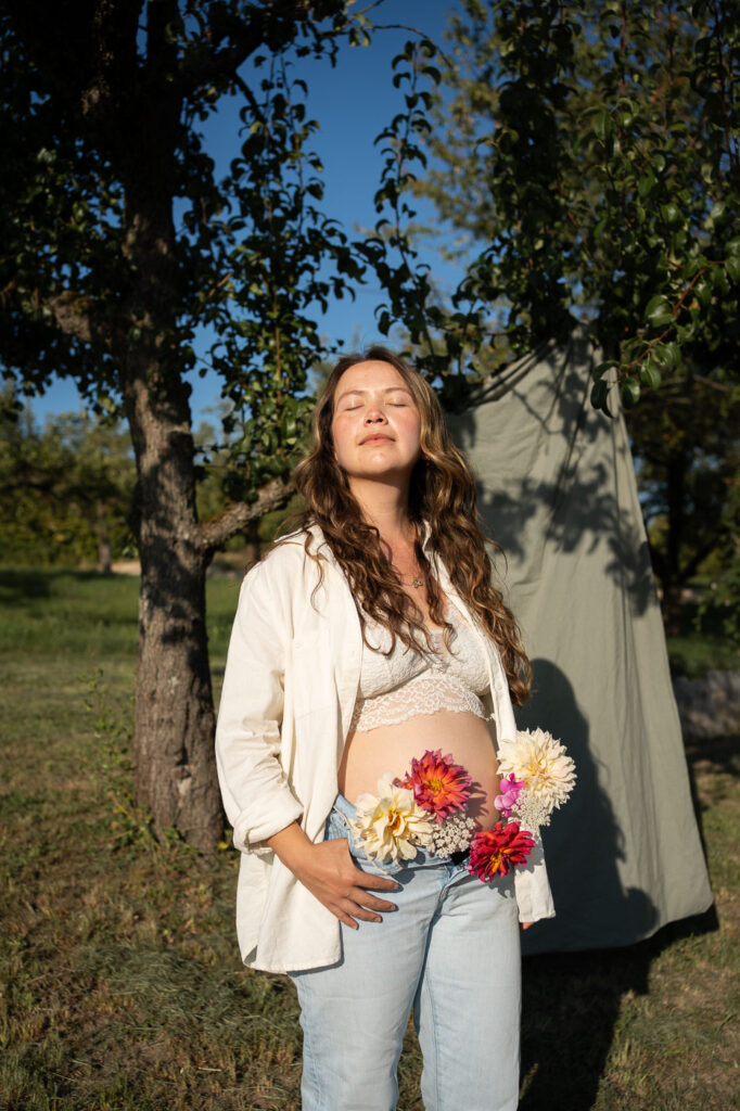 Authentisches Babybauch-Shooting: Schwangere Frau mit Blumen im Arm
