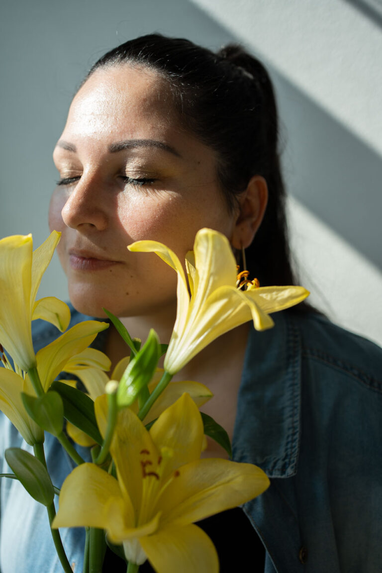 Nahaufnahme: Frau riecht an gelben Lilien, sanfte Stimmung