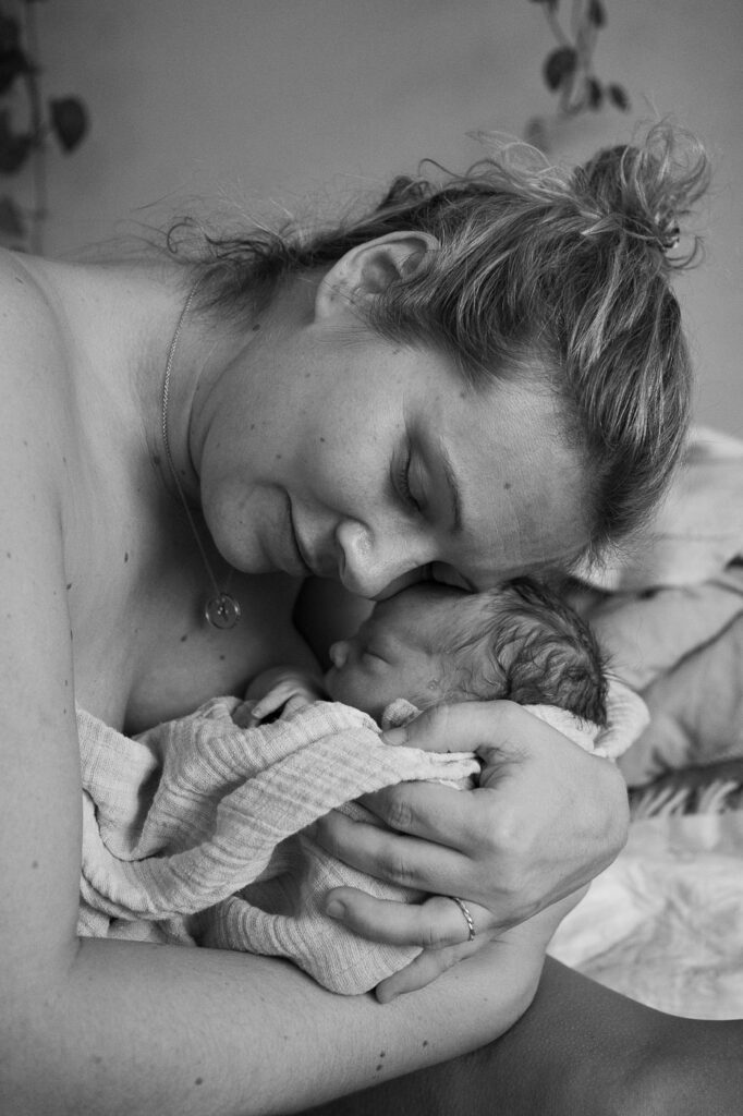 schwarz weiß Geburtsfoto, Mama lehnt ihren Kopf auf den Kopf ihres neugeborenen Kindes, emotionale Geburtsfotografie Esslingen, sensible Geburtsfotografie Stuttgart
