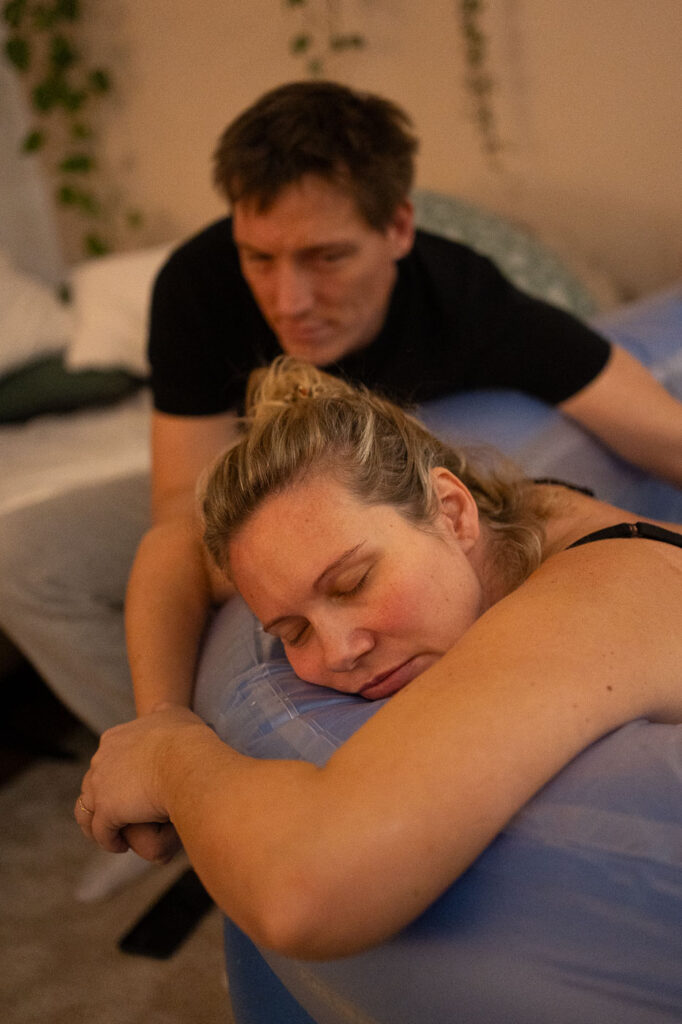Frau liegt im Geburtspool, Mann hält ihre Hand, Geburtsfotografie Esslingen, sensible Geburtsfotografie Stuttgart