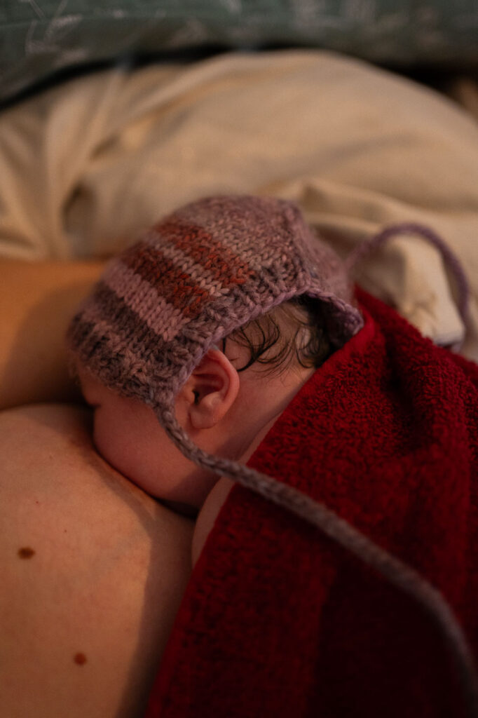Köpfchen eines Neugeborenen auf Brust während des Stillens, Geburtsfotografie Esslingen